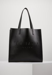 Czarna skórzana torba typu tote z wytłoczonym logo "TED BAKER LONDON", o strukturalnym kształcie, długich uchwach i teksturowanym wykończeniu.