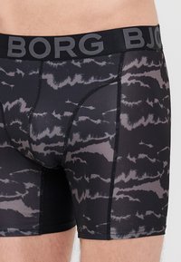 Fekete boxer alsónadrág szürke absztakt mintával, elasztikus derékrésszel, amelyen a "BORG" felirat található, és sima anyagú textúrával.