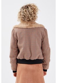 Brun rutigt bombarjacka med krage av konstfuskpäls, ribbade svarta manchetter och nederkant, texturerad tyg med puffad design, sedd bakifrån.