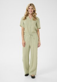 Jumpsuit vert clair à manches courtes, avec un devant à boutons, une taille élastique avec cordon de serrage et une coupe à jambes larges, fabriqué à partir d'un tissu texturé.