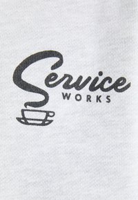 Gray fabric featuring the text "Service Works" in bold black font, accompanied by a coffee cup graphic underneath.