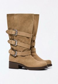 Bottes mi-mollet en daim couleur fauve avec trois sangles latérales réglables et boucles argentées, talons blocs et bouts arrondis.