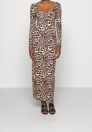 Vrouwelijk model draagt een lang mouw, enkel-lang luipaardprintjurk met zwarte sandalen met hak, staand tegen een effen lichte achtergrond.