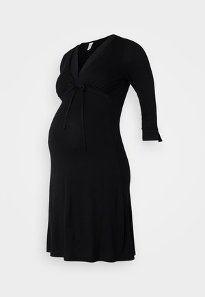 Zwarte zwangerschap jurk met een V-halslijn, driekwart mouwen en een strikdetail onder de buste; zachte, rekbare stof voor comfort.