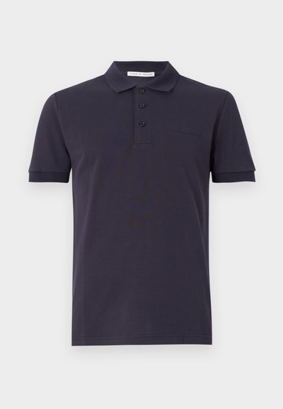 Tumed polo särk, mis on valmistatud puuvillast, klassikalise kraega, kolmeknöppliku, lühikeste varrukatega ja diskreetse brändingu ning rinnal.