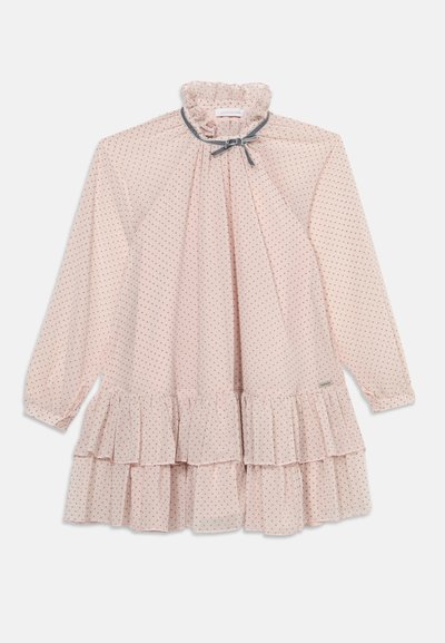 Robe rose clair à manches longues avec de petits pois, col à volants avec un nœud, et ourlet à volants superposés.