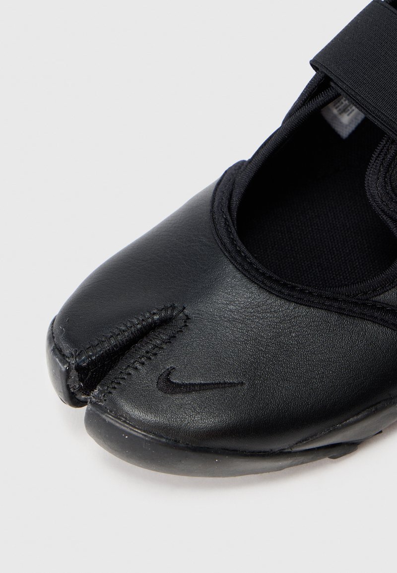 Zwarte lederen schoen met een ronde neus en gesplitst ontwerp. Voorzien van een zwarte elastische band en een gestructureerd oppervlak. Nike-logo aan de zijkant.