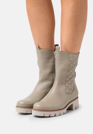 Light grey leather ankle boots with a quilted side panel, round toe, and chunky white platform sole. Zipper closure for easy wear.