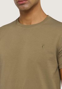 Olivgrön kortärmad t-shirt i mjuk bomull, med rund halsringning och en subtil broderad logotyp på bröstet.