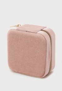 Kwadratowe, miękkie różowe etui na biżuterię z zaokrąglonymi krawędziami i złotym zamkiem, częściowo zamknięte na białym tle.