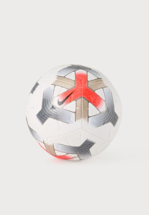 Ballon de football blanc avec des motifs géométriques gris, beige et rouges ainsi qu'un petit logo swoosh noir sur un fond clair uni.