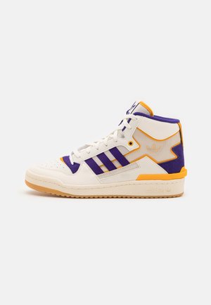 Wysokie białe tenisówki Adidas z fioletowymi paskami, pomarańczowymi akcentami i gumową podeszwą, widoczne z boku na jednolitym tle.