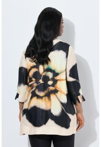 Bluse mit Blumenmuster in schwarz und creme, ausgestattet mit Dreiviertelärmeln und aus leichtem, fließendem Stoff. Auffälliges Blumendetail auf der Rückseite.