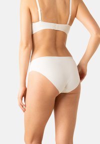 Ensemble de sous-vêtements blanc à côtes avec des bretelles ajustables et un design sans coutures. Texture douce avec une silhouette minimaliste.