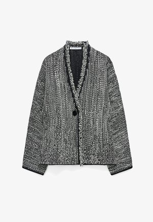 Cardigan lavorato a maglia marmorizzato in bianco e nero con maniche lunghe, chiusura con un solo bottone nero e bordo con frange lungo il davanti e lo scollo.