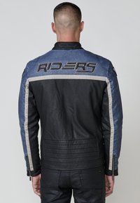 Crna i plava kožna motoristička jakna s "RIDERS" logotipom, kontrastnim trakama i teksturiranim panelima na leđima.
