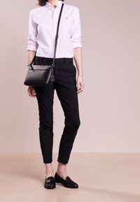 Ljust rosa randig skjorta med knappar, svarta skräddarsydda byxor och svarta läder loafers. Svart axelremsväska med texturerad yta och metallaccenter.