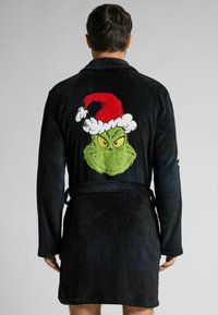 Czarny szlafrok z miękkiego materiału, z dużym nadrukiem kreskówkowego Grincha w czerwonej czapce Mikołaja na plecach. W zestawie pasek do wiązania.