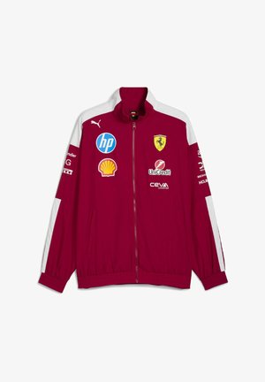 Crvena lagana jakna s bijelim detaljima, puni zatvarač, visoki ovratnik, istaknuti brend logotipi i elastične manžete. Prikladna za svakodnevno nošenje ili sportske događaje.