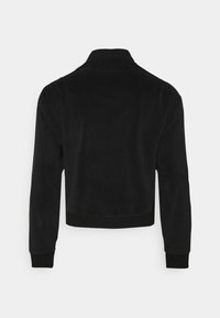 Chaqueta negra de pana con cuello, puños y cintura acanalados. Presenta un diseño sencillo con una textura lisa y sin herrajes visibles.