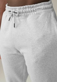 Graue Sweatpants mit elastischem Bund und Kordelzug. Der Stoff hat eine weiche, strukturierte Oberfläche. Verfügt über eine Seitennaht für einen maßgeschneiderten Look.
