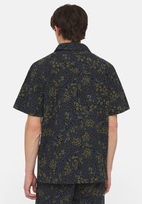 Camicia a maniche corte nera con un motivo astratto in verde, blu e crema. Presenta una vestibilità comoda e un design con colletto.