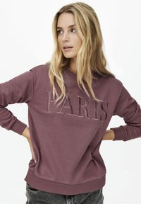 Μωβ φούτερ με την ένδειξη "PARIS" σε ανάγλυφα γράμματα, ριγέ μανσέτες και στρίφωμα, χαλαρή εφαρμογή, μαλακή υφή υφάσματος και χαλαρό σχέδιο.