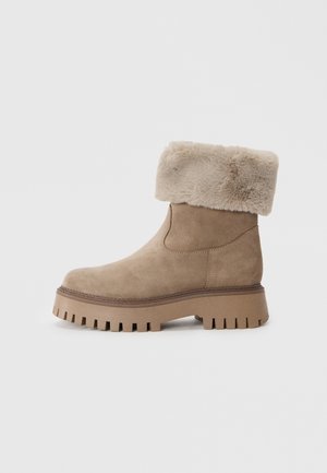 Ankelsko i semsket skinn i lys beige med en faux fur-krage. Har en kraftig, teksturert gummisåle og elastiske paneler på siden for enkel påkledning.