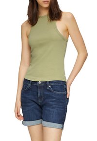 Top senza maniche verde oliva con un design aderente, abbinato a pantaloncini di jeans blu scuro, con orlo piegato e tasche frontali.