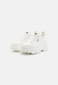 Fehér sneaker, masszív talppal, textúrált felsőrésszel, fűzős záródással és húzófüllel. Az oldalán egy kis kék logó található.
