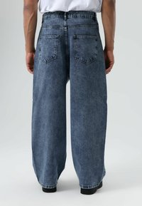 Lichtblauwe oversized spijkerbroek met een hoge taille, grote achterzakken en een licht vervaagde structuur, met een rechte pijp.