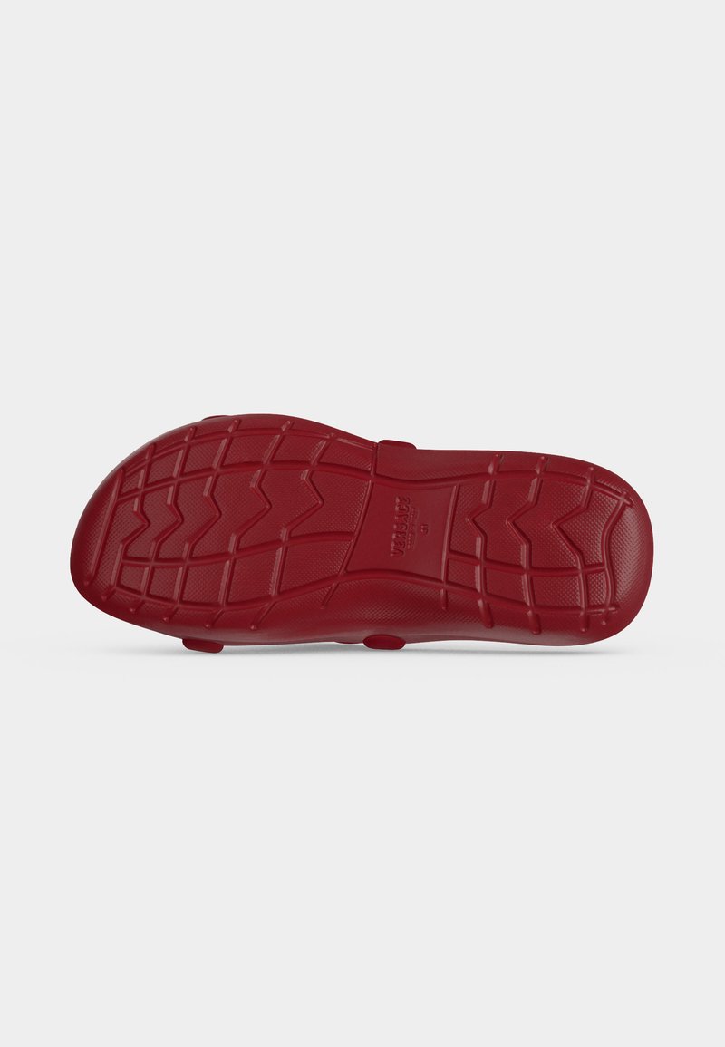 Sole of a red shoe with textured grip patterns and brand name embossed in the center.