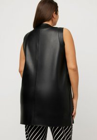 Schwarze ärmellose Weste aus Kunstleder. Glatte Textur mit geradem Schnitt, ausgestattet mit seitlichen Taschen und dezenten Nähten.