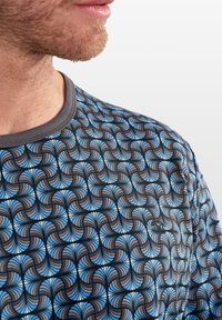 Kurze-Shirt mit einem geometrischen Wirbelmuster in Blau und Schwarz, das einen grauen Ausschnitt und ein kleines Logodetail auf dem Stoff aufweist.