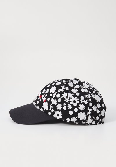 Gorra negra con patrones florales blancos, visera curvada, el diseño de la tela presenta varias formas y tamaños de flores, incluye un logo rojo en el lateral.