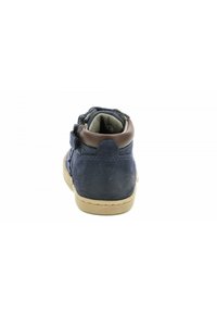 Zapatilla alta de ante azul marino con un cuello de tobillo de cuero marrón y suela de goma color beige; presenta tiras de velcro y detalles de costura.