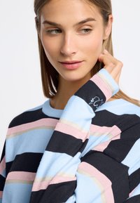 Sweter w paski z poziomymi niebieskimi, czarnymi, różowymi i brązowymi liniami. Posiada okrągły dekolt oraz logo na rękawie. Miękka dziana tekstura.