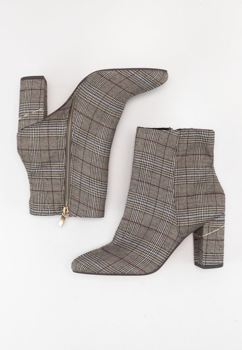 Paire de bottines pour femmes en tissu à carreaux beige, talons blocs et fermetures éclair latérales dorées, posées à plat sur une surface blanche.