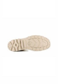 Semelle de chaussure en beige clair avec un motif de semelle robuste, dotée de sections surélevées, de rainures et de trous de drainage pour une traction et une flexibilité accrues.