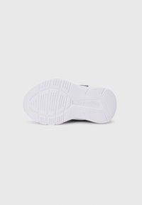 Sole of a white Skechers sneaker showing tread pattern and logo, isolated on a plain light background.