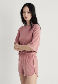 Rosa, texturerad, kortärmad sweatshirt med rund halsringning, matchad med shorts som har resårmidja och sidopartier.