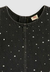 Mustavärinen farkkukangas, jossa on pyöreä pääntie, koristeltu ripotelluilla strassikivillä ja näkyvällä Levi's-tunnuksella lähellä ykköskohdan ykköspistettä.
