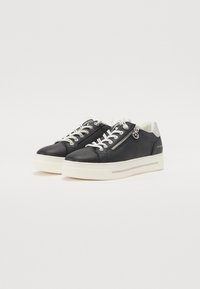 Baskets en cuir noir avec semelle blanche, détail de zip argenté et design à lacets. Présentent une texture lisse et un design minimaliste.