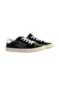 Zapatillas de cuero negro con cordones blancos y un acento blanco en el talón. Presenta un detalle del logo dorado en el lateral y una suela de goma de color claro.