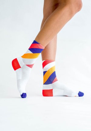 Colorful ankle socks featuring a pattern of diagonal stripes in red, orange, purple, and white, with a contrasting blue toe. Cotton blend material.