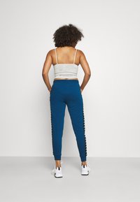 Blå joggers med en avsmalnande passform, med svarta sidostråk. Kombinerat med en ljusgrå, ribbad crop-top och vita sneakers.