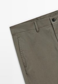 Olivgrön bomullbyxor med flat front, sidofickor och en knappstängning, med en mjuk textur och rena linjer.