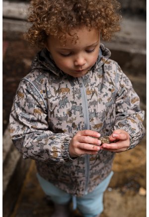Lysegrå jakke med dyreprint, elastiske manchetter og lynlås foran, kombineret med lyseblå shorts. Barn holder en lille sten.