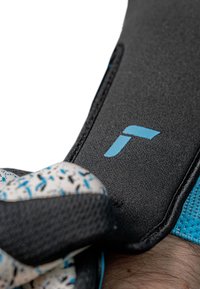 Gant de sport noir et bleu avec une zone de prise texturée, un matériau élastique et un logo bleu sur la bande du poignet ; vue de près.