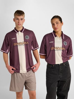 Junger Mann und Frau tragen passende bordeaux- und cremefarbene gestreifte Poloshirts mit dem "SWARM International"-Logo und stehen vor einem schlichten Hintergrund.